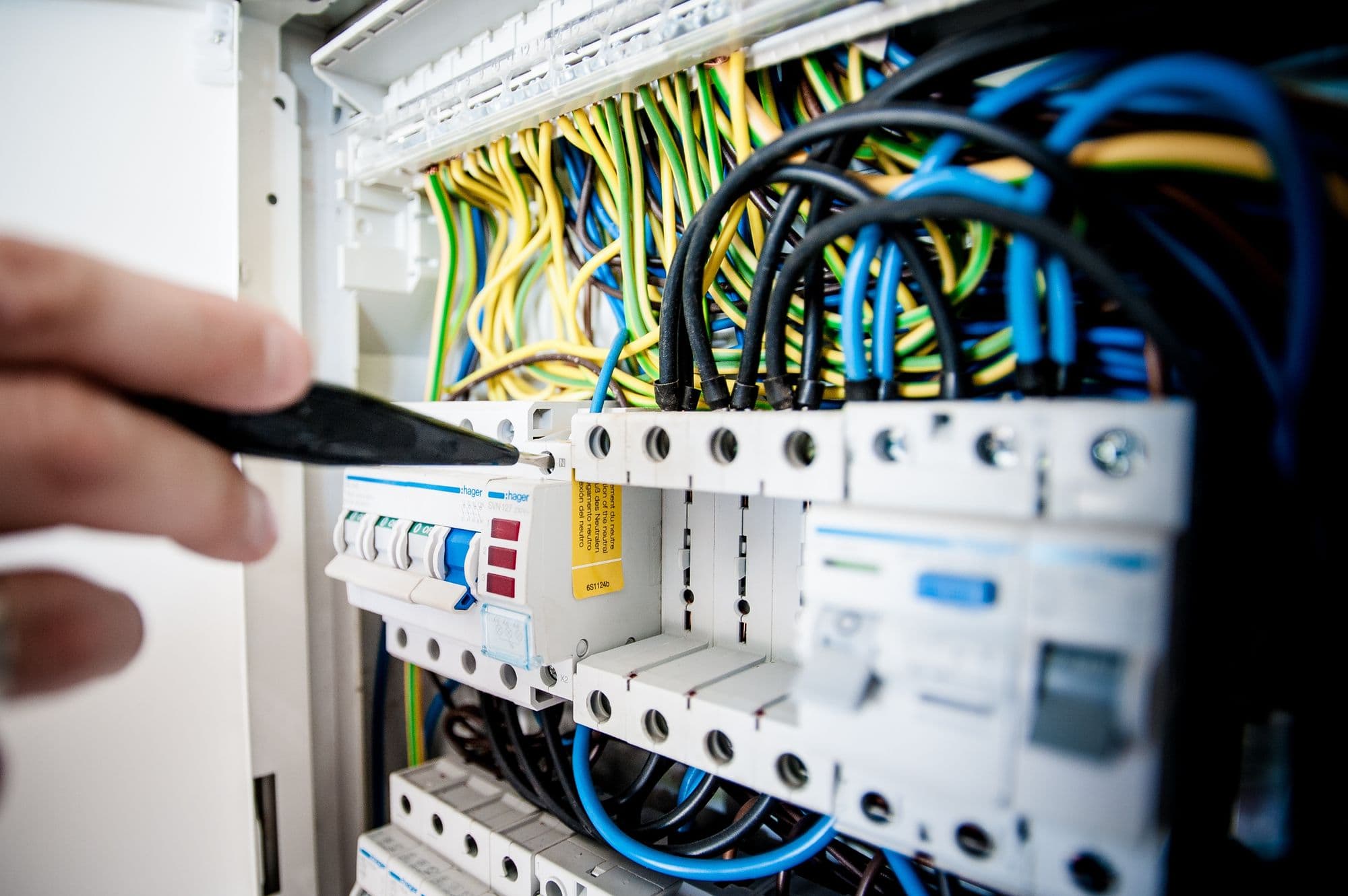 Electrician working inside a consumer unit with a screwdriver